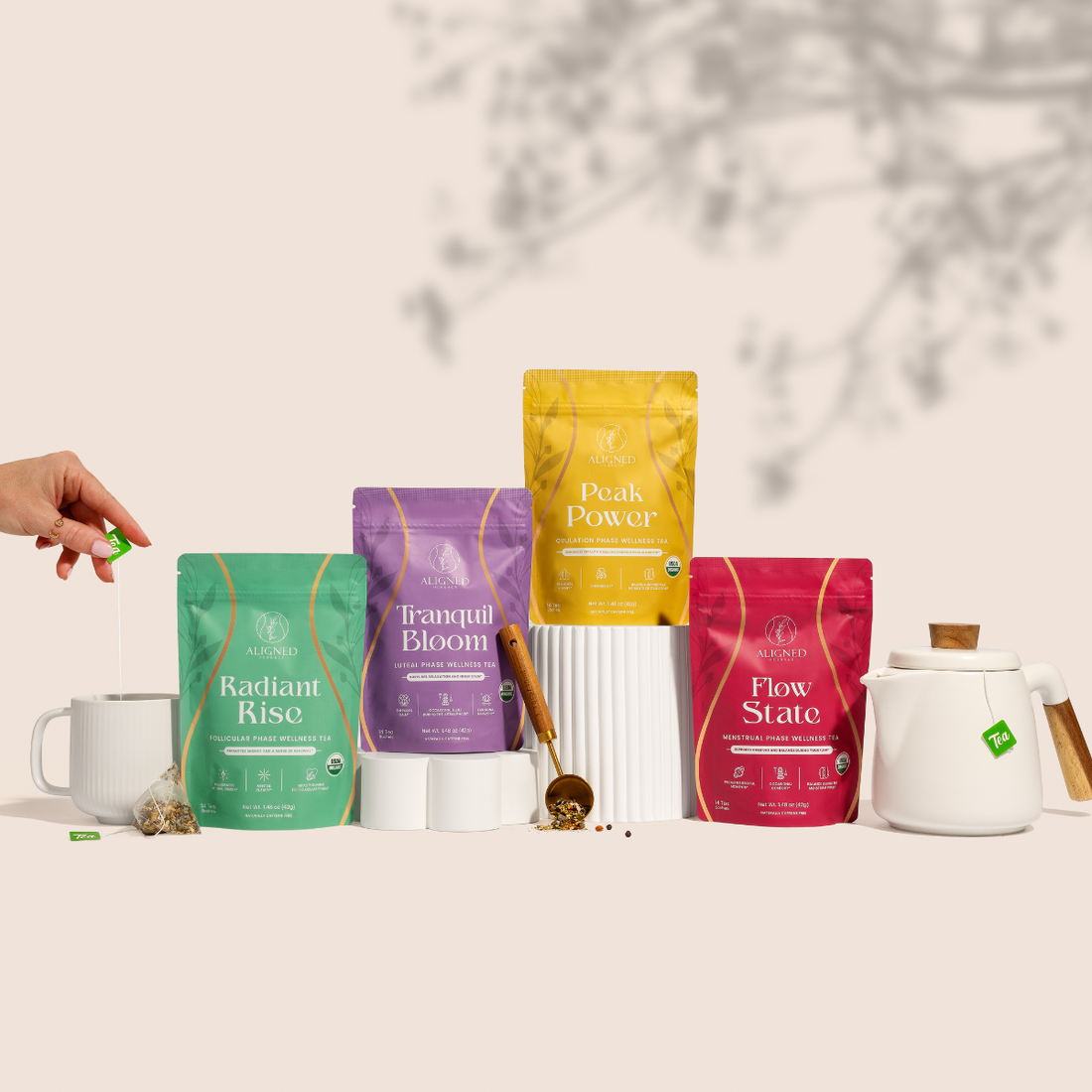 Assorted packages of tea or health products with a hand reaching for one, on a neutral background.